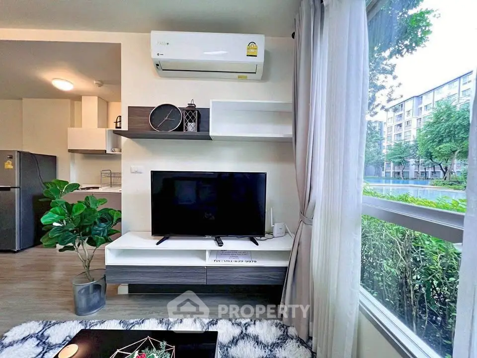 Modern living room with large window, TV unit, and air conditioning in stylish apartment.