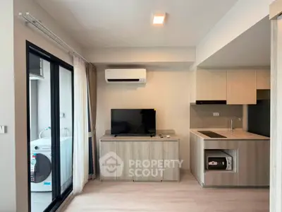 Modern living room with sleek kitchen and balcony view, featuring air conditioning and washing machine.