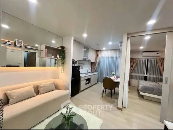 Modern open-plan living room and kitchen with cozy bedroom in a stylish apartment.
