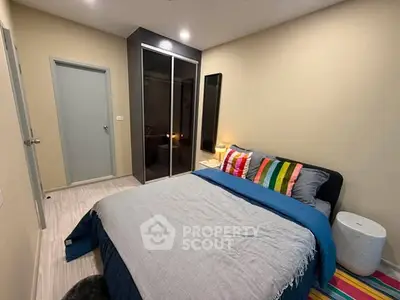 Cozy bedroom with modern decor and colorful accents, featuring a sleek wardrobe and comfortable bedding.