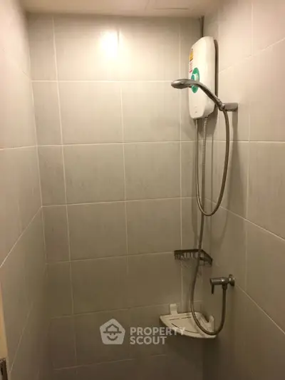 Compact bathroom with modern shower unit and tiled walls, ideal for efficient space utilization.