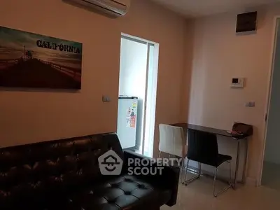 Modern living room with black leather sofa and dining area, featuring stylish decor and air conditioning.