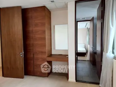 Spacious bedroom with wooden wardrobe and vanity, leading to a cozy adjoining room.