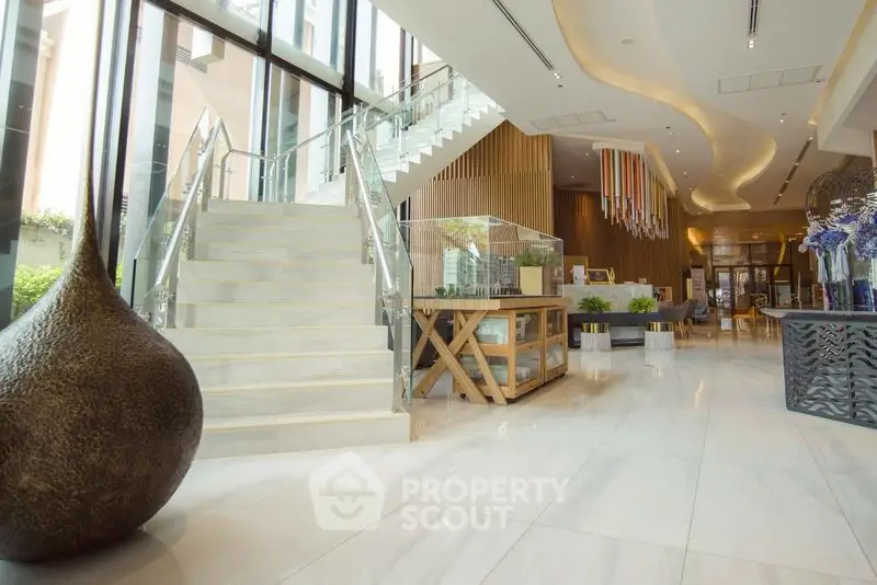 Luxurious modern lobby with elegant staircase and stylish decor in a high-end building.