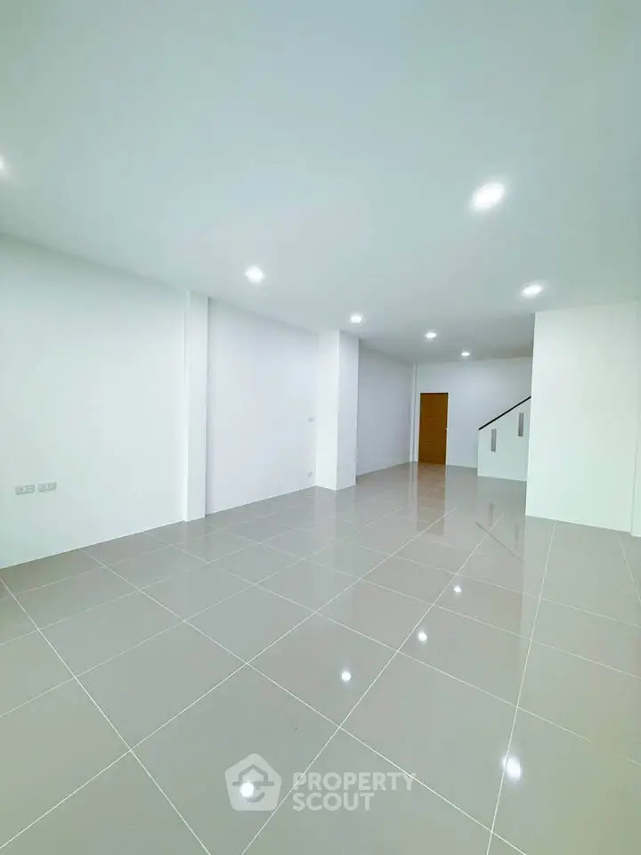 Spacious modern living room with glossy tiled floors and bright lighting.