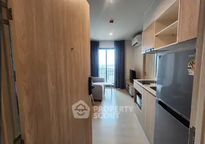 Modern apartment interior with open kitchen and living room, featuring sleek appliances and natural light.