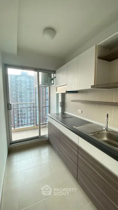 Modern kitchen with sleek cabinetry and balcony view in urban apartment