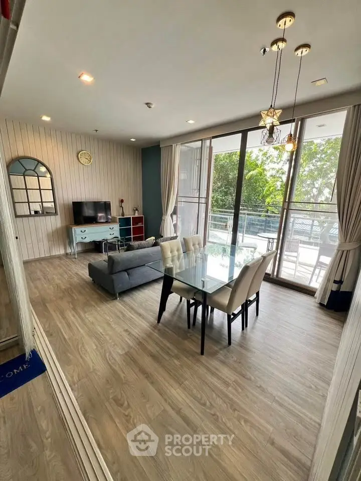 Spacious modern living room with elegant dining area and large windows overlooking greenery.