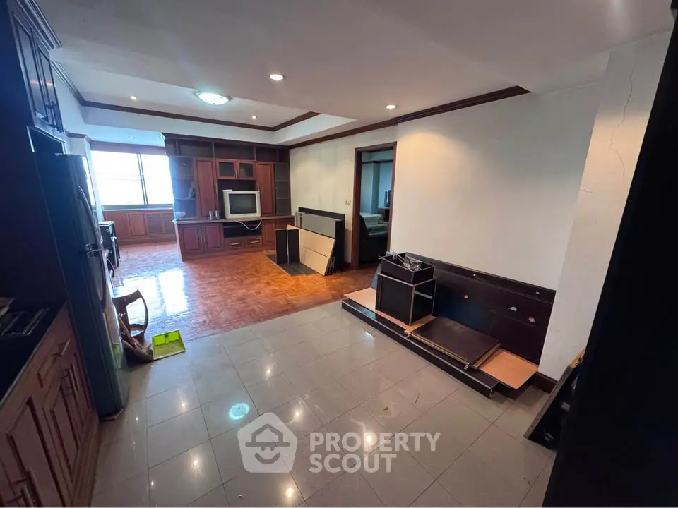 Spacious living room with built-in wooden cabinets and large window view.