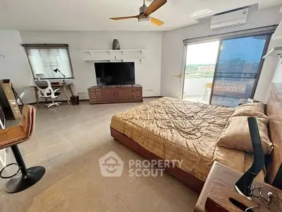 Spacious bedroom with modern decor and balcony access, featuring a large TV and stylish furnishings.
