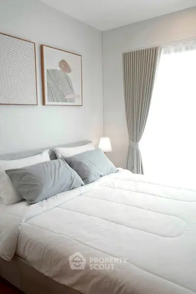 Cozy bedroom with modern decor and natural light from large window.