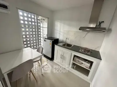 Modern compact kitchen with sleek design, featuring a small dining area and stainless steel appliances.