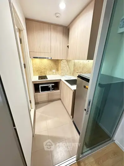 Modern compact kitchen with sleek wooden cabinets and built-in appliances