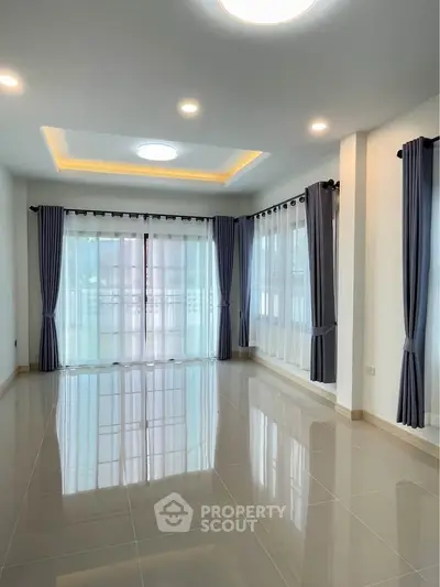 Spacious and bright living room with elegant curtains and glossy tiled floor.