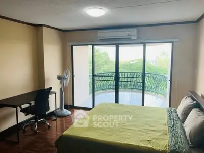 Spacious bedroom with balcony and natural light, featuring a desk and air conditioning for comfort.