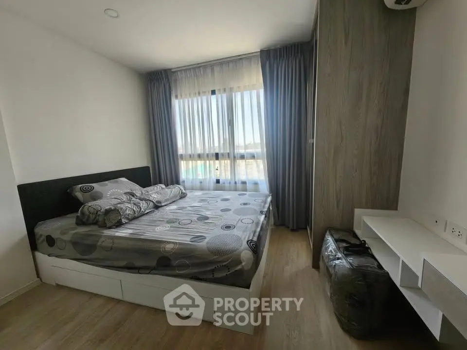 Modern bedroom with stylish decor and large window offering natural light and scenic views.