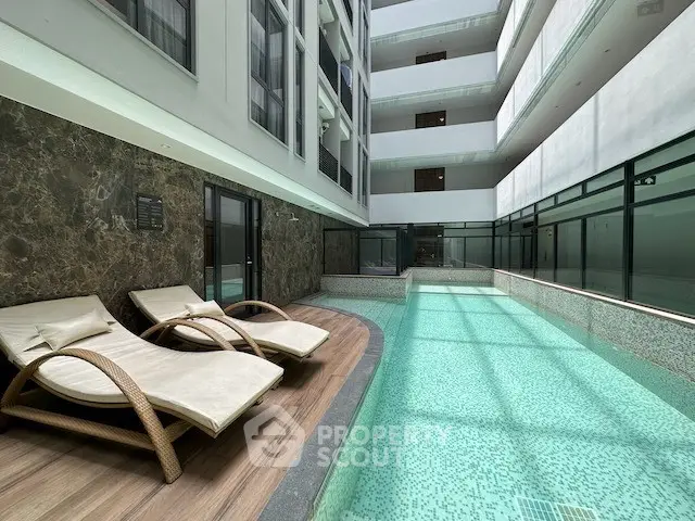 Luxurious indoor pool area with elegant lounge chairs in a modern residential building.