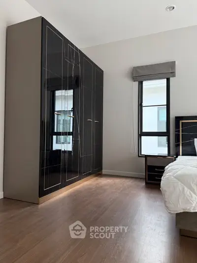 Modern bedroom with sleek black wardrobe and large window