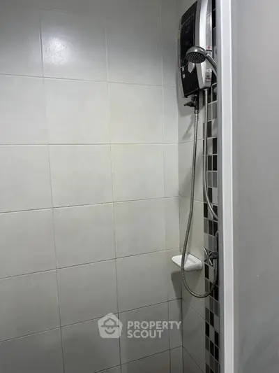Compact bathroom shower area with modern water heater and tiled walls