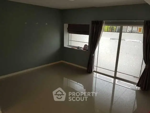 Spacious empty room with glossy tiled floor and large window for natural light.