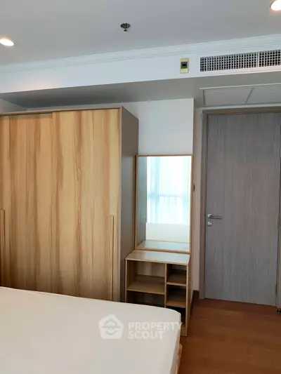Modern bedroom with wooden wardrobe and vanity, featuring sleek design and ample natural light.