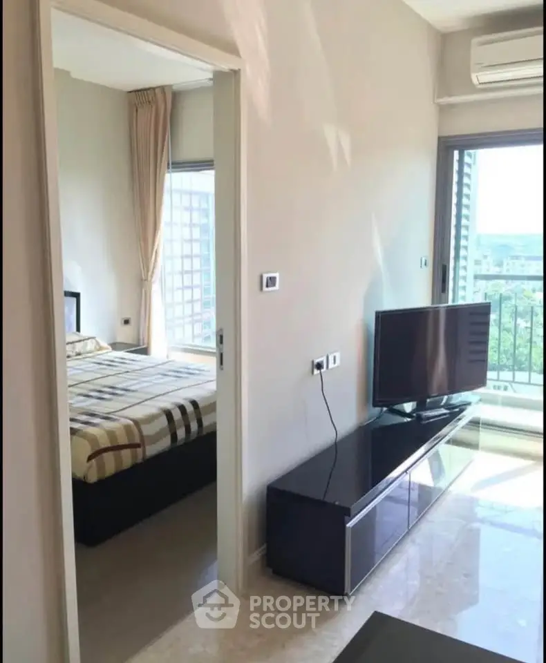 Modern apartment interior with bedroom and living area, featuring sleek design and natural light.