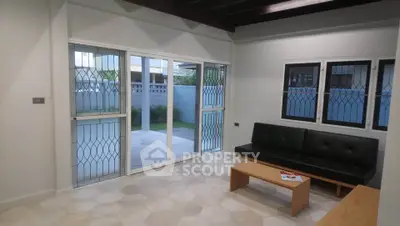Modern living room with sliding doors opening to a patio, featuring a sleek black sofa and wooden coffee table.