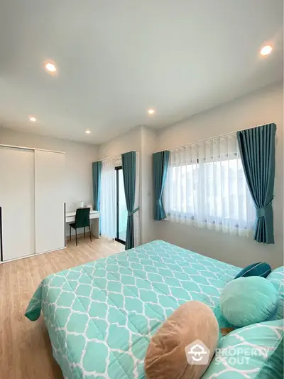 Spacious bedroom with stylish teal decor and natural light