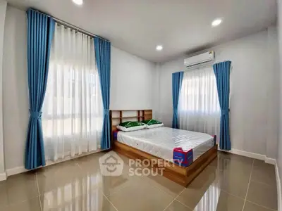 Spacious bedroom with modern design, featuring large windows and elegant blue curtains.