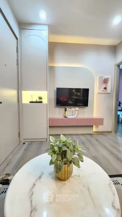 Modern living room with stylish decor and wall-mounted TV, featuring a marble table and elegant lighting.
