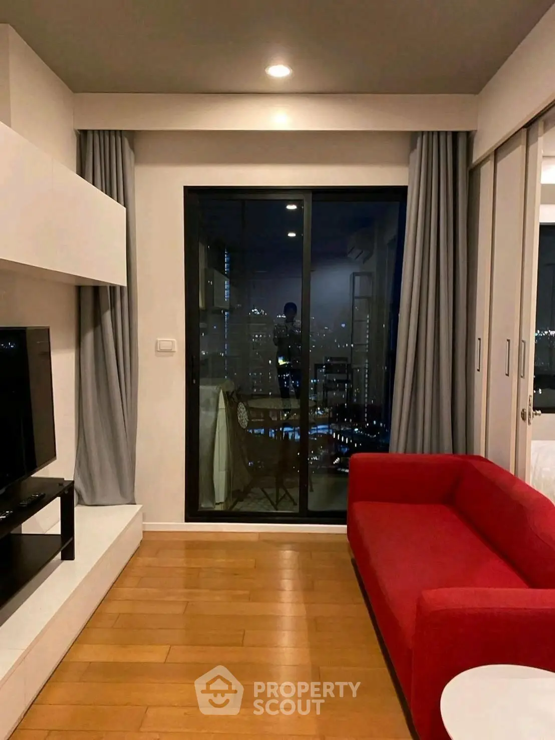 Modern living room with red sofa and city view balcony at night