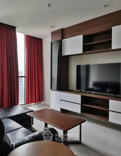 Modern living room with sleek furniture and large TV, featuring floor-to-ceiling windows and red curtains.