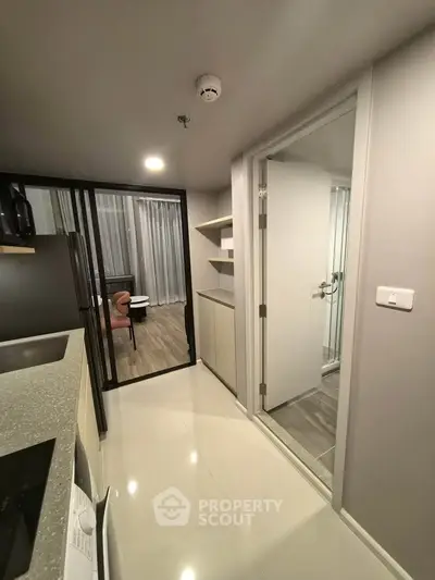 Modern apartment interior with sleek kitchen and open layout leading to a cozy living area.