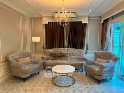 Elegant living room with chandelier, plush seating, and large windows for natural light.