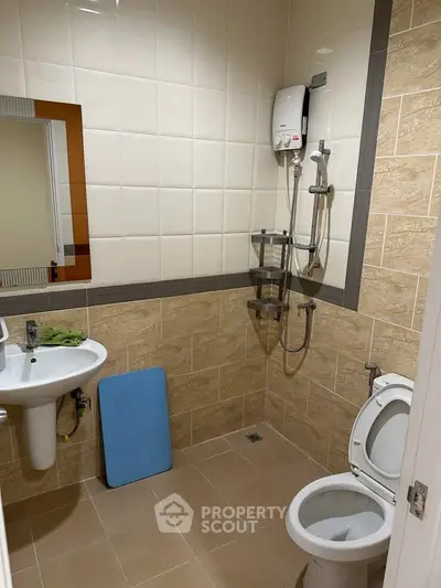 Modern bathroom with shower, toilet, and sink in a tiled setting.
