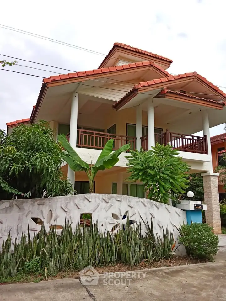 Charming two-story house with red-tiled roof and lush garden