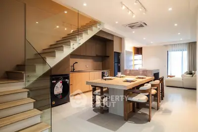 Modern open-plan kitchen and dining area with stylish staircase and cozy living room.