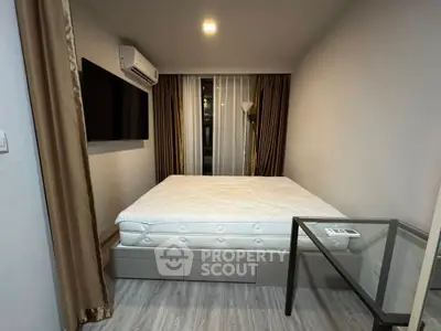 Modern bedroom with minimalist design, featuring a large bed, wall-mounted TV, and sleek glass table.