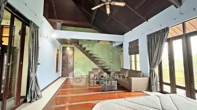 Spacious living room with modern furniture and high ceiling, featuring a unique staircase design.