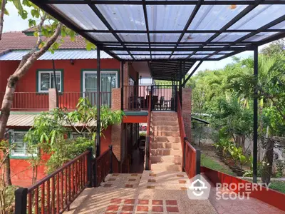 Charming red house with covered walkway and lush garden view