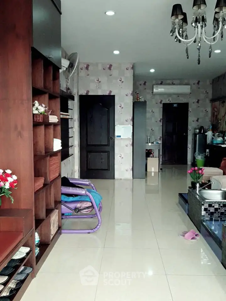 Elegant interior with glossy tiled flooring, wooden shelving, and a chic chandelier complementing the floral wallpaper, creating a modern yet cozy ambiance.