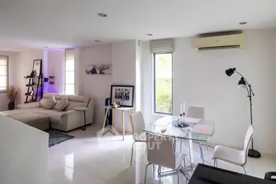 Modern living room with dining area, featuring sleek furniture and natural light.