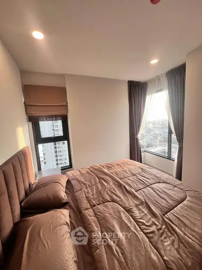 Cozy bedroom with large windows offering stunning city views, perfect for relaxation and comfort.