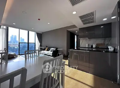 Modern open-layout kitchen and living room with city view, sleek design and natural light.