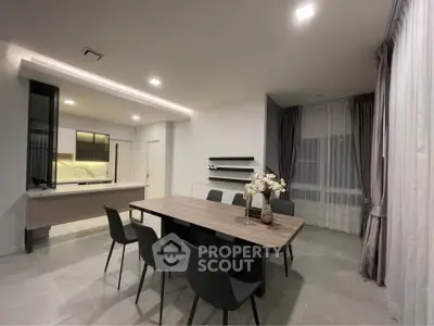 Modern dining area with sleek table and chairs, open layout kitchen, and elegant lighting.