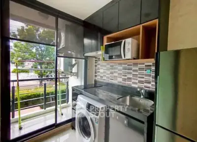 Modern kitchen with washing machine, microwave, and balcony view