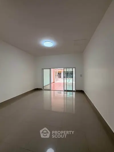 Spacious empty room with sliding glass doors leading to a balcony, perfect for customization.