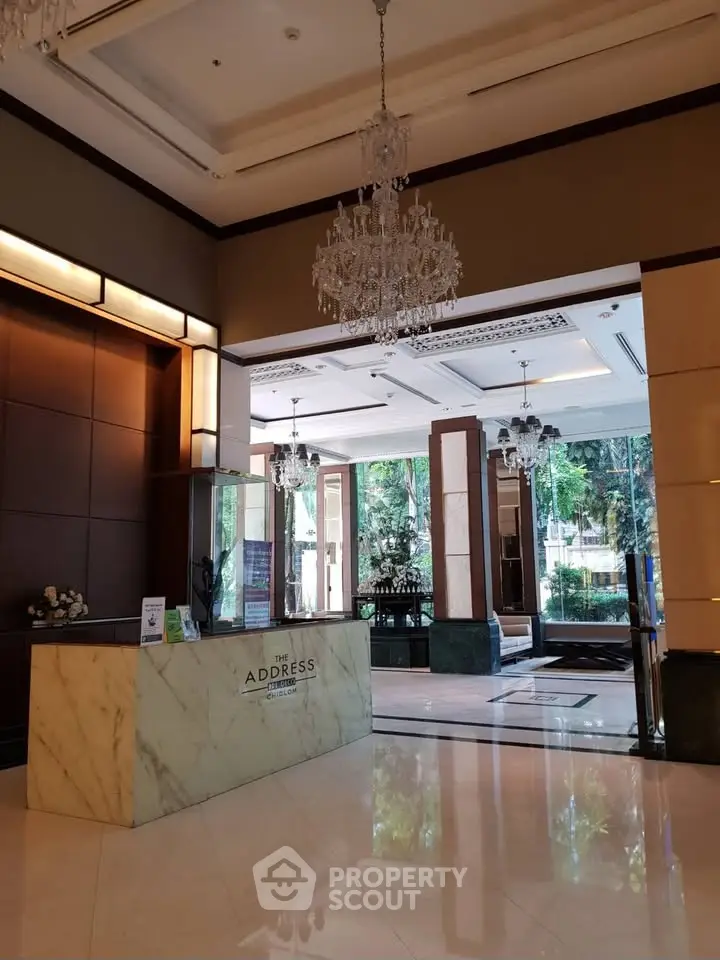 Luxurious building entrance with elegant chandeliers and marble reception desk