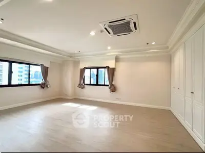 Spacious empty room with large windows and elegant ceiling design in modern apartment.