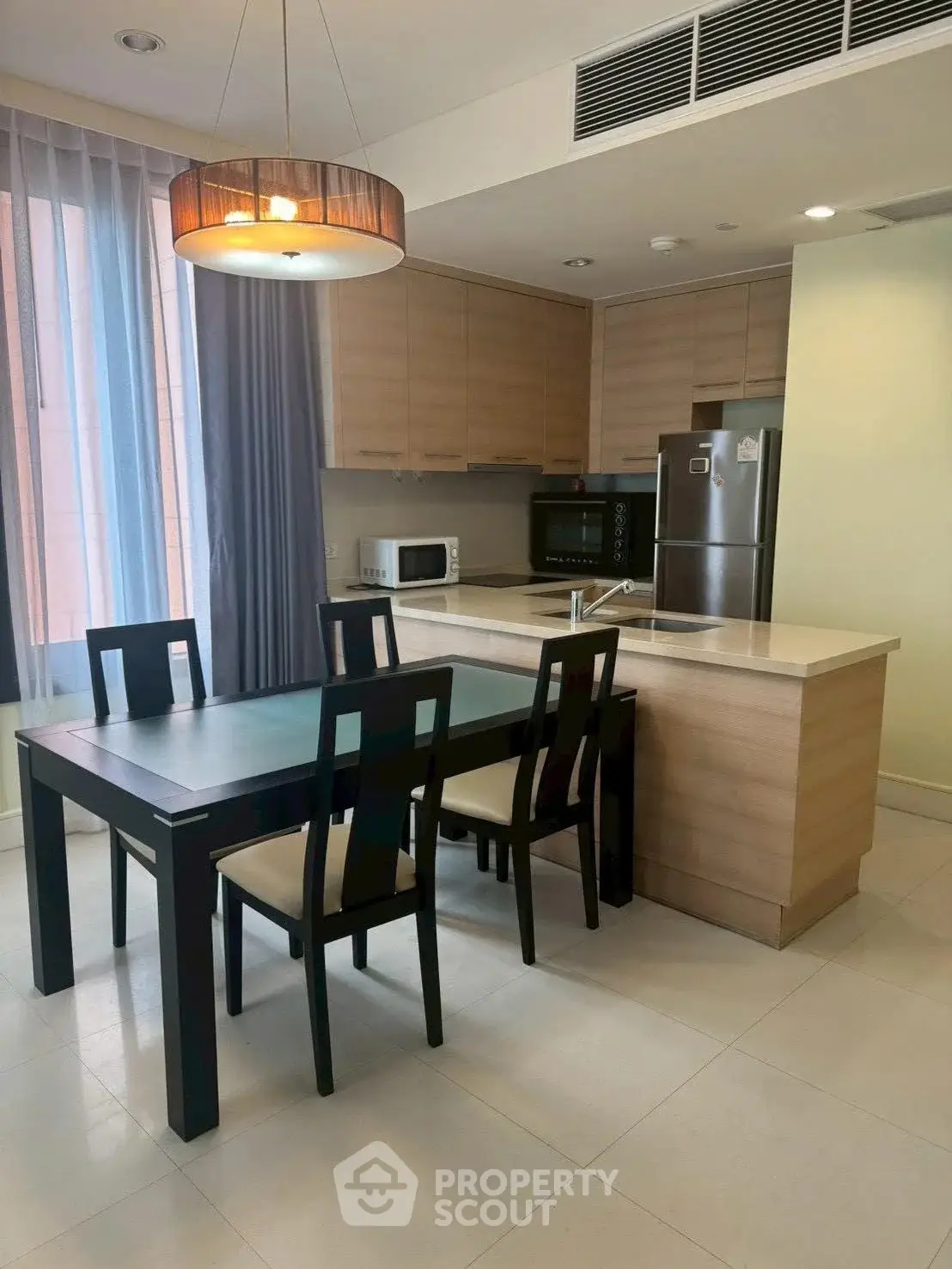 Modern kitchen with dining area, featuring sleek cabinetry and stainless steel appliances.